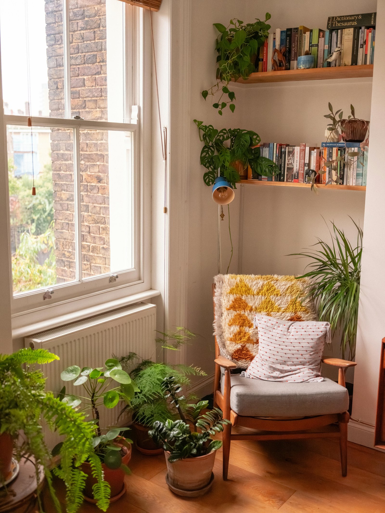 Coin lecture scandinave avec fauteuil en laine, coussins colorés et plantes