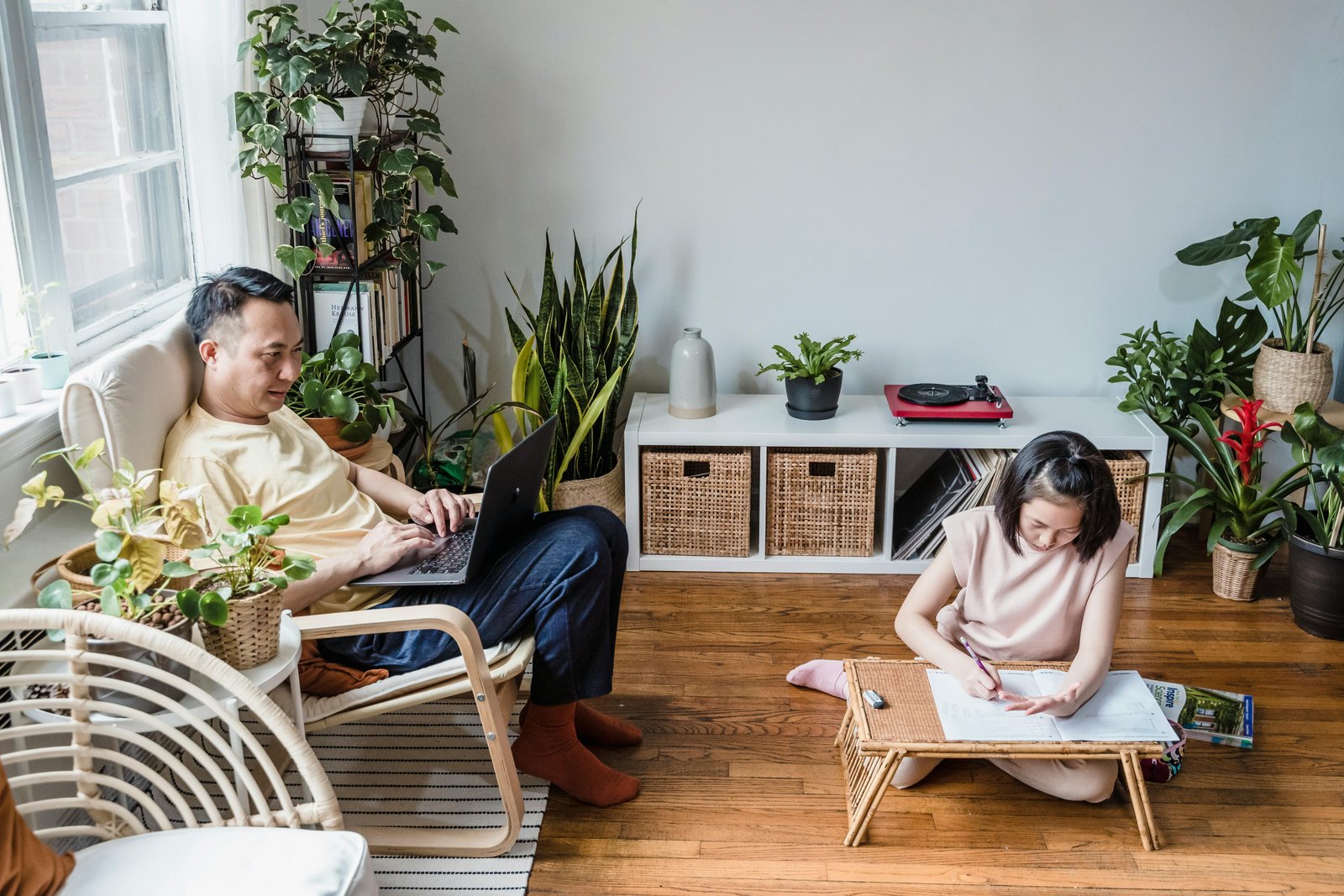 Famille dans un salon modulable, espace partagé entre bureau et coin détente, plantes vertes en arrière-plan